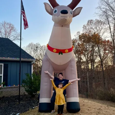 Laura and daughter standing in front of reindeer.